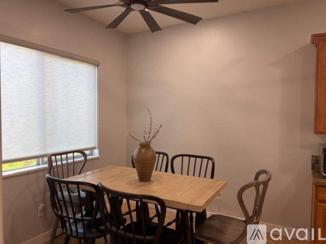 A dining room with a table, chairs, and a ceiling fan.