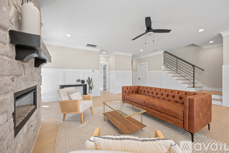 A living room with a brown couch and a stone fireplace.