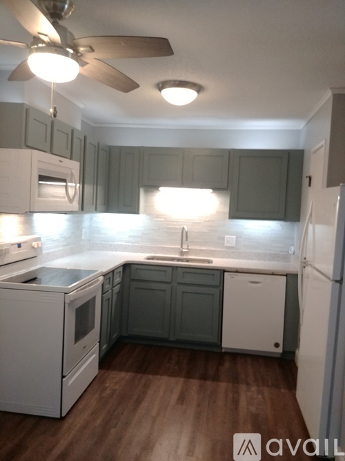 A kitchen with white appliances and wooden floors.