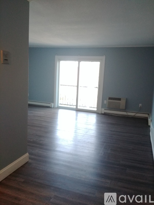 A room with a large window and wooden flooring.
