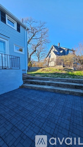 A blue tiled patio area with a house and trees in the background.