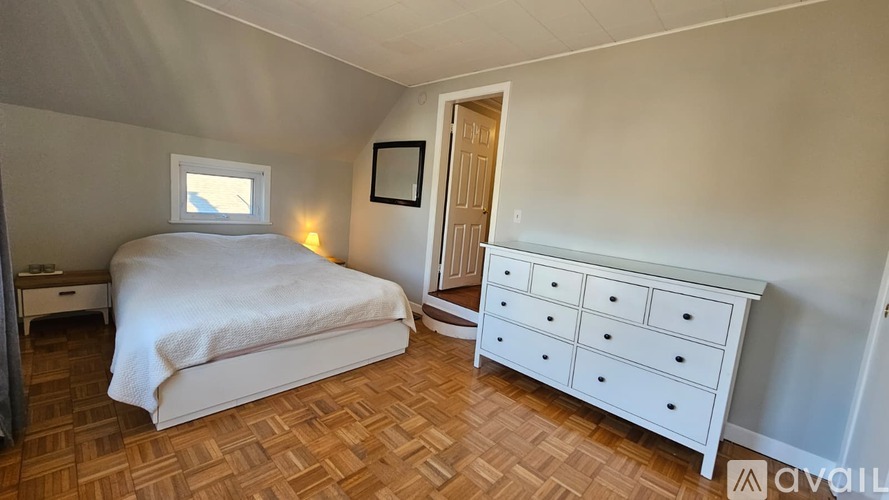 A bedroom with a bed, dresser, and window.