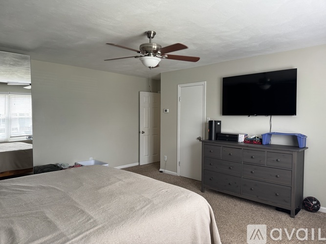 A bedroom with a bed, dresser, and ceiling fan.