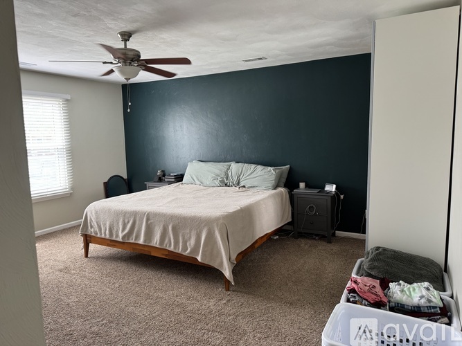A bedroom with a bed, a ceiling fan, and a nightstand.