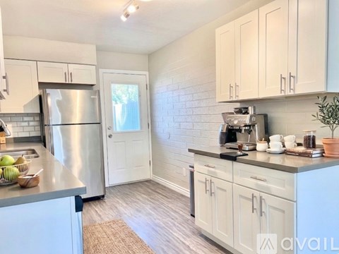 A kitchen with white cabinets and a stainless steel refrigerator.