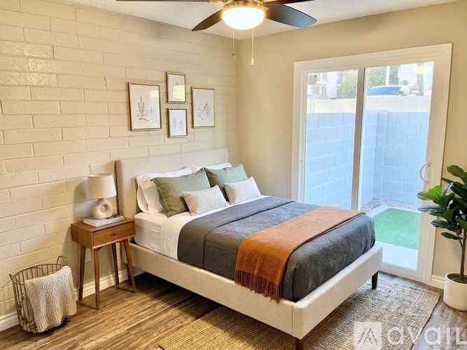 A bedroom with a bed, a nightstand, a lamp, a ceiling fan, and a plant.