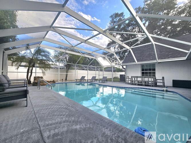 A pool under a white roof with trees in the background.