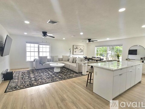 A spacious living room with a white kitchen island and a rug in the middle.