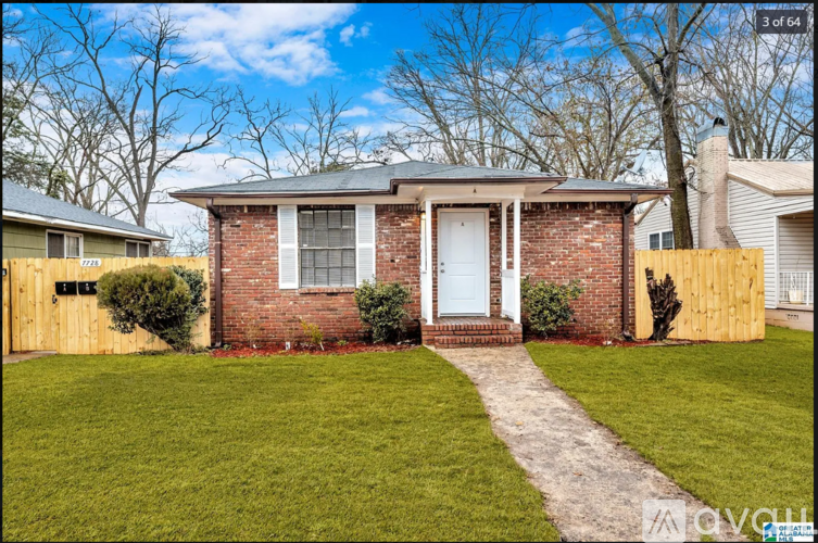 A small brick house with a white door and a small front yard.