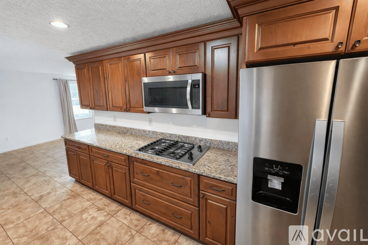A kitchen with wooden cabinets and a stainless steel refrigerator.