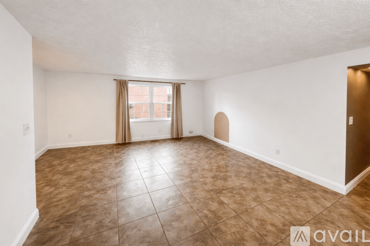 A room with brown tiled flooring and a window with curtains.