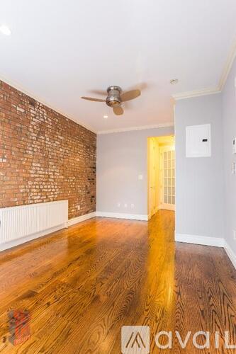 A room with a wooden floor and a brick wall.