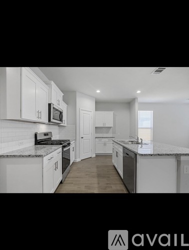 A kitchen with white cabinets and a granite countertop.