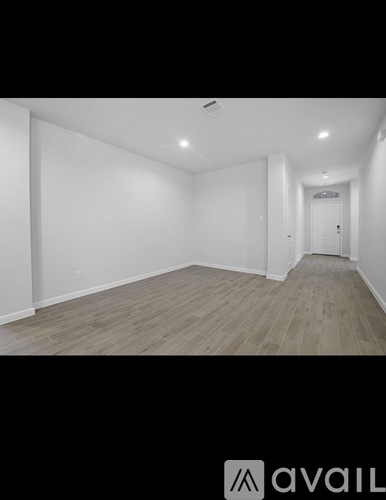 A spacious room with wooden flooring and white walls.