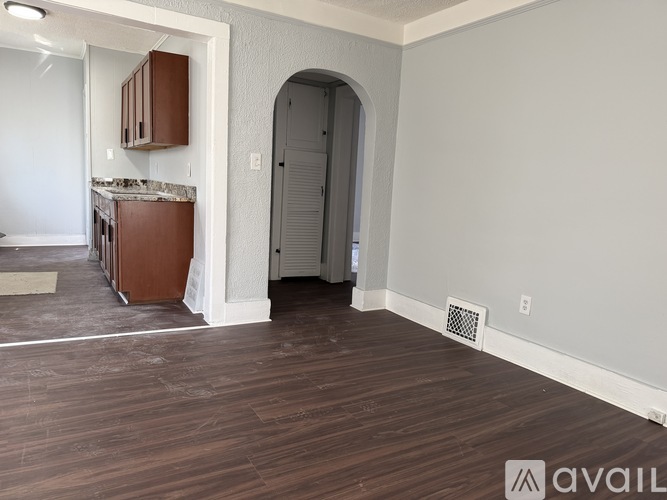 A room with wooden flooring and a kitchen area with brown cabinets.