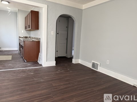 A room with wooden flooring and a kitchen area with brown cabinets.