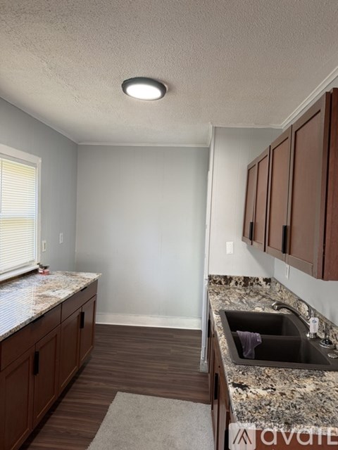 A room with wooden flooring and a door leading to another room.