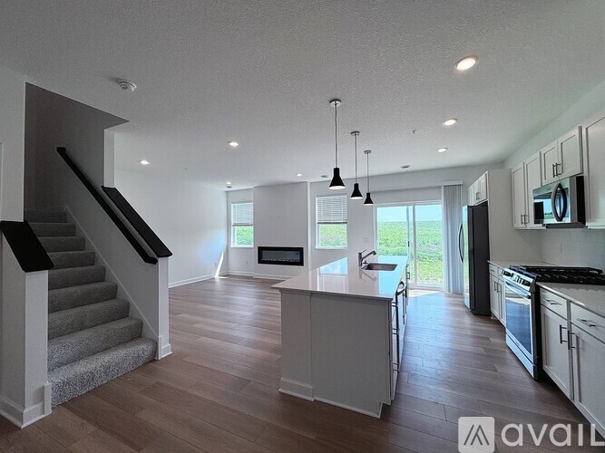 A modern kitchen with a staircase on the left side.