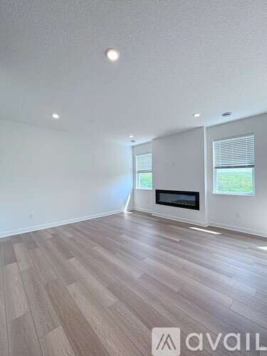 A spacious room with wooden flooring and a fireplace.