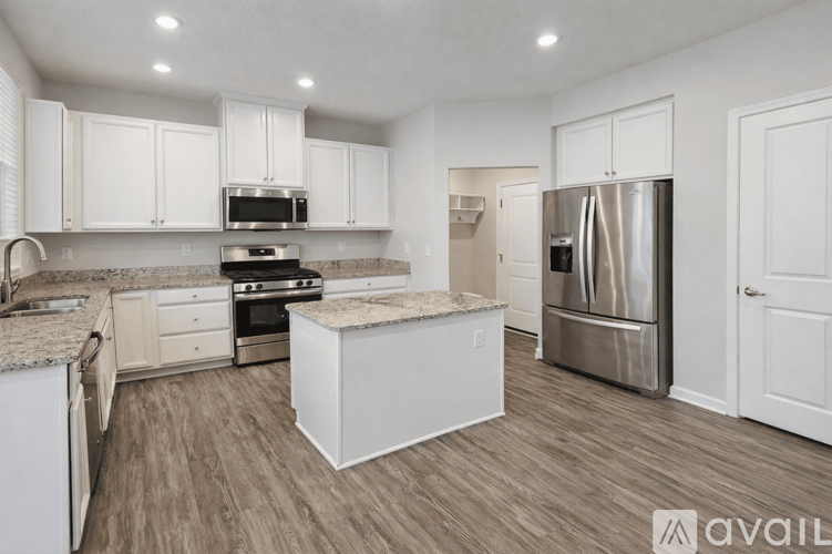 A kitchen with white cabinets and a stainless steel refrigerator.