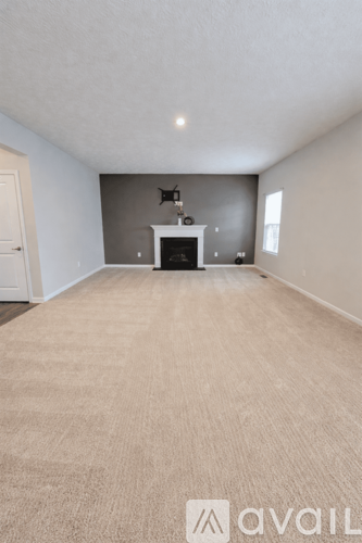 A spacious room with a fireplace and carpeted floor.