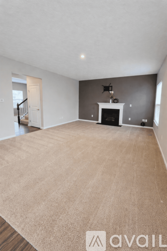 A large empty room with a carpeted floor and a fireplace.