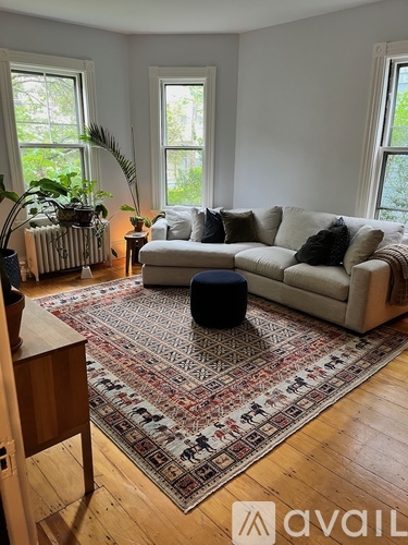 A living room with a rug, a couch, and a table.