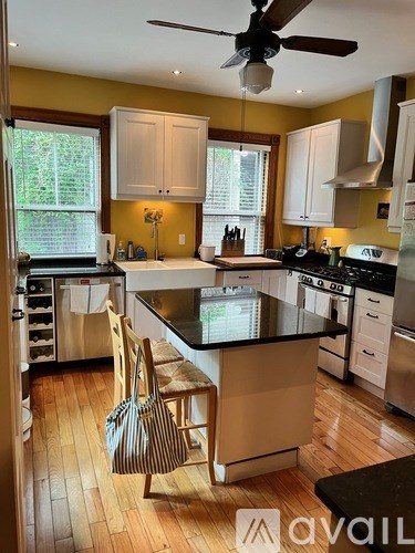 A kitchen with a black counter top and wooden floors.