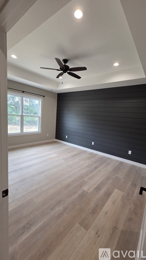 A room with a ceiling fan and wooden flooring.