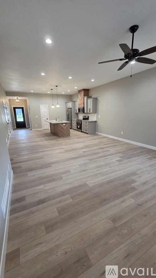 A spacious room with wooden flooring and a ceiling fan.