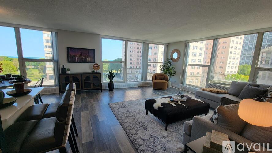 A living room with a couch, a chair, a coffee table, and a large window overlooking a cityscape.