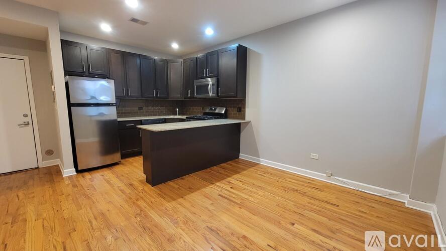 A kitchen with wooden floors and black cabinets.