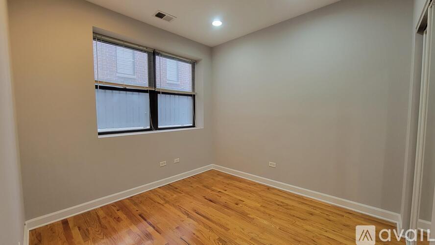 A room with wooden flooring and a window with blinds.