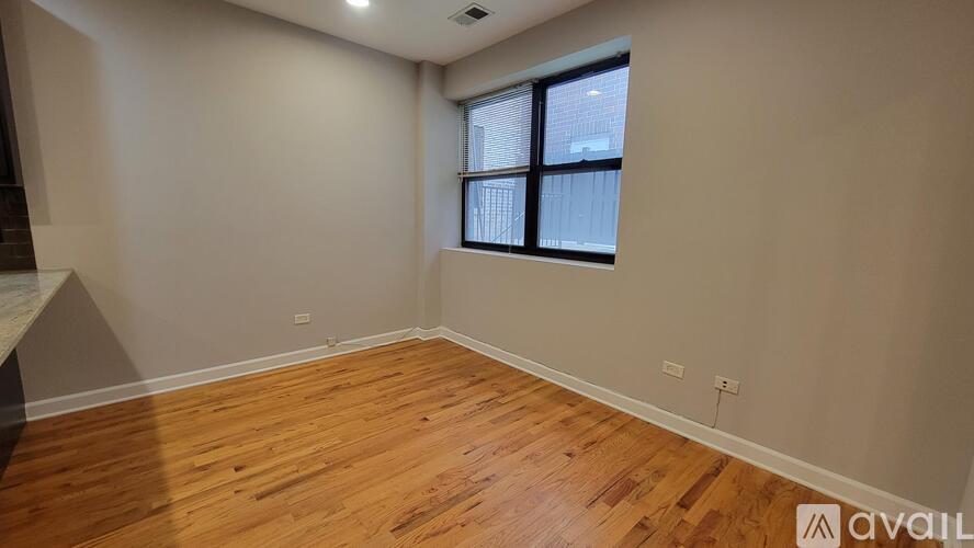 A room with wooden flooring and a window with blinds.