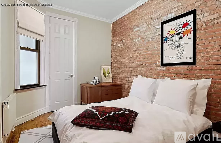 A bedroom with a white bed and a brick wall.