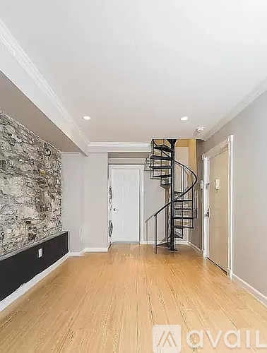 A spacious hallway with a spiral staircase and wooden flooring.