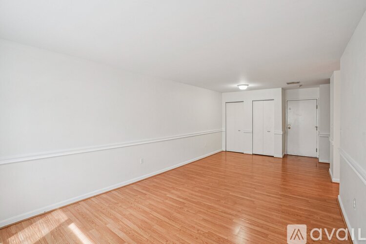 A room with wooden flooring and white walls, with a door on the right side.