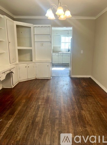 A kitchen with white cabinets and wooden floors.