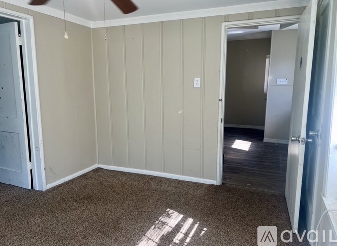 A room with a carpeted floor and a ceiling fan.