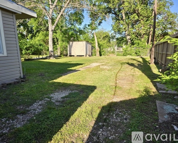 A backyard with a grassy area, a dirt path, and trees.