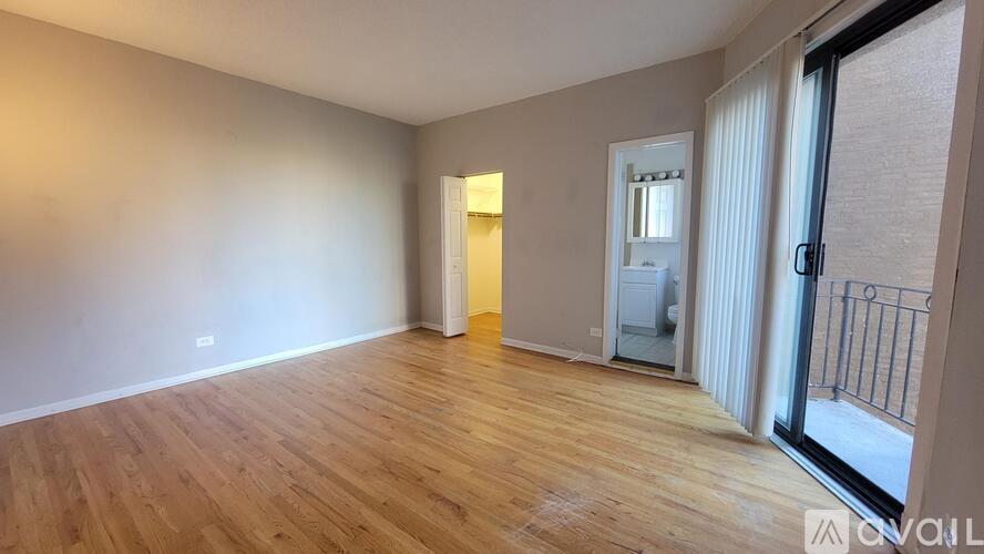 A room with wooden flooring and a sliding glass door leading to a balcony.