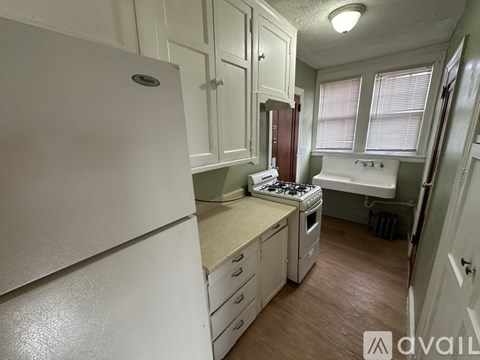 A small kitchen with white appliances and wooden floors.