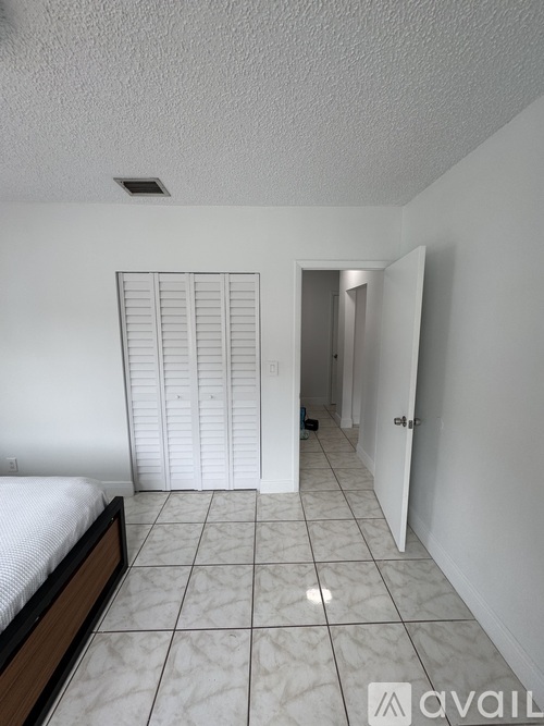 A bedroom with a bed, tiled floor, and a closet.