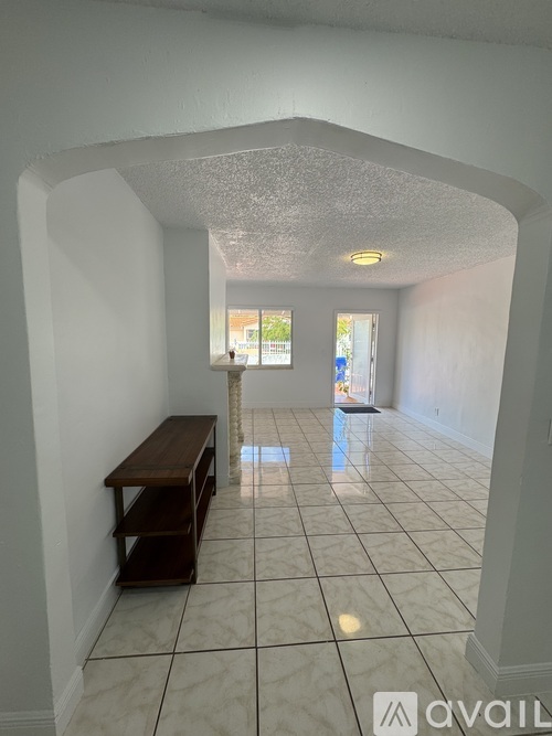A hallway with a bench and a tiled floor.
