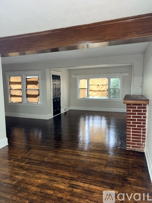 A room with wooden floors and a brick fireplace.