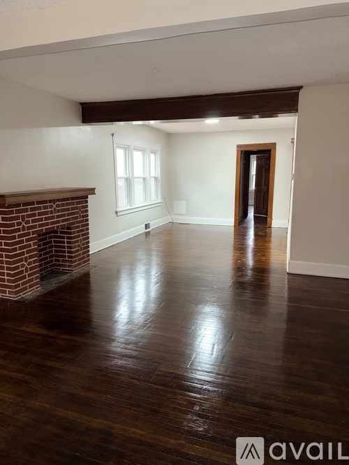 A room with a brick fireplace and wooden floors.
