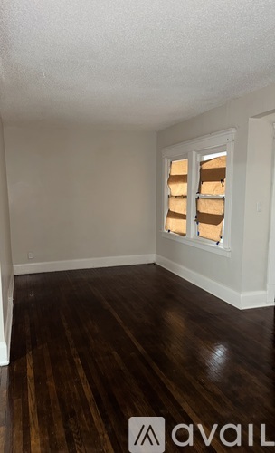 A room with wooden floors and a window with no curtains.