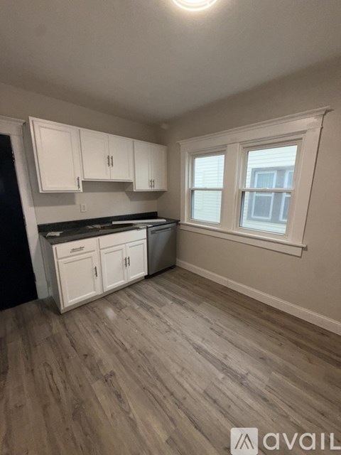 A kitchen with white cabinets and a wooden floor.