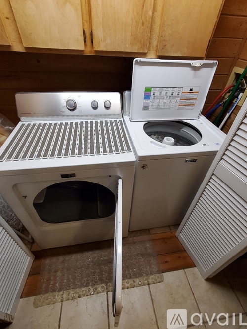 A white oven with a grill on top and a white dishwasher with the door open.