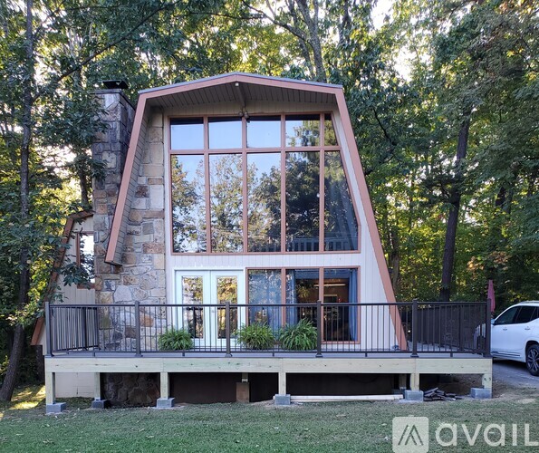 A modern house with a triangular roof and large windows is surrounded by trees.